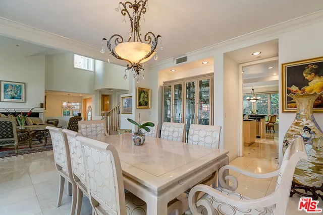 a view of a dining room and livingroom with furniture wooden floor a rug a potted plant and a chandelier