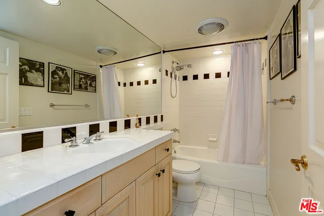 a bathroom with a double vanity sink toilet mirror and shower