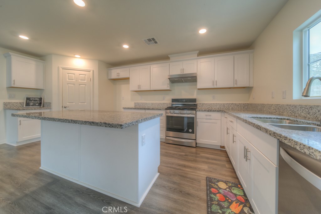 9596 Trailhead Lane Moreno Valley, CA 92557 - Photo 32 of 67 a kitchen with kitchen island granite countertop a sink a stove top oven a counter space and cabinets
