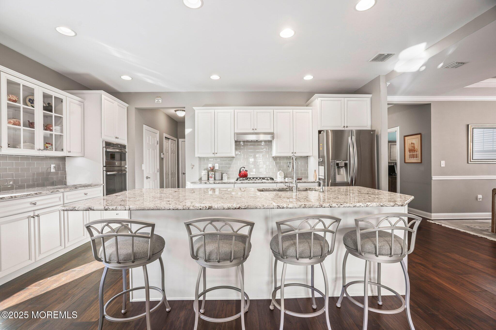 57 Harvest Ridge Road Howell, NJ 07731 - Photo 14 of 39 a kitchen with stainless steel appliances a dining table chairs and white cabinets