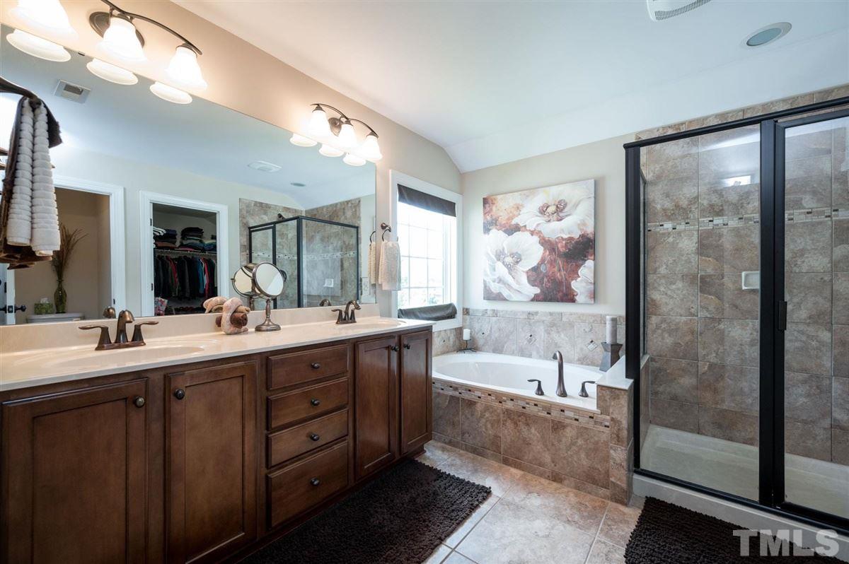 1004 Bianco Drive Raleigh, NC 27607 - Photo 18 of 30 a bathroom with double vanity sinks a large mirror and a bathtub