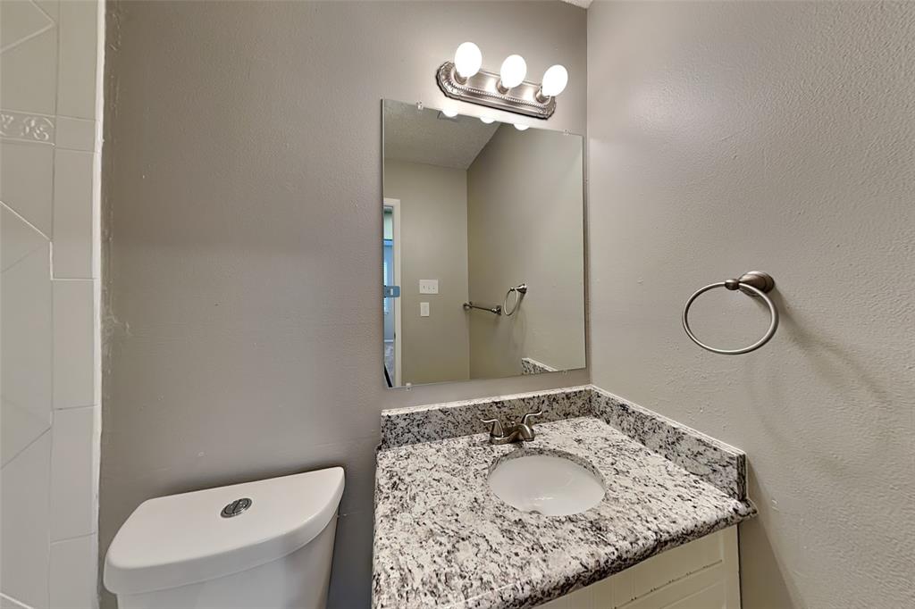 1504 Homestead Street Flower Mound, TX 75028 - Photo 19 of 22 a bathroom with a granite countertop sink a toilet and a mirror