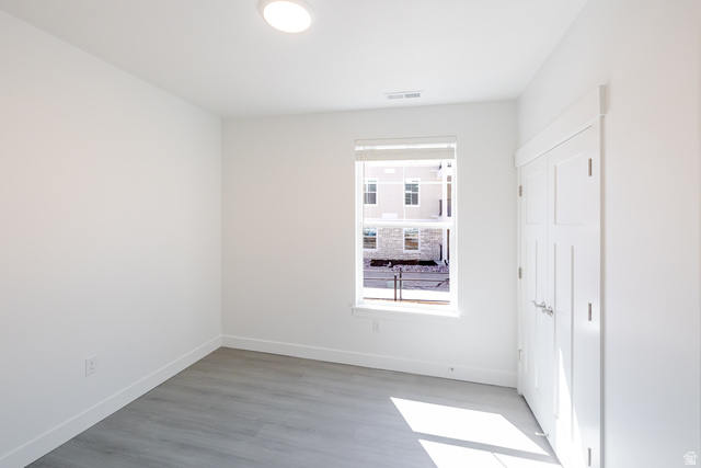 4664 South 680th West, Unit S102 Mapleton, UT 84664 - Photo 8 of 16 Neutral-toned room featuring a single window, recessed ceiling lighting, gray wood-finish flooring, white baseboards, and a bi-fold closet door
