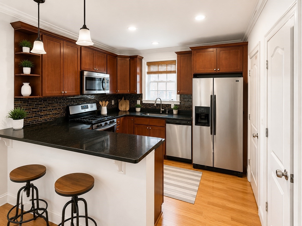 a kitchen with stainless steel appliances granite countertop a sink a stove a refrigerator a counter with chairs and cabinets