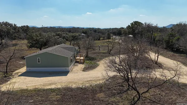 a aerial view of a house with a yard and mountain view in back