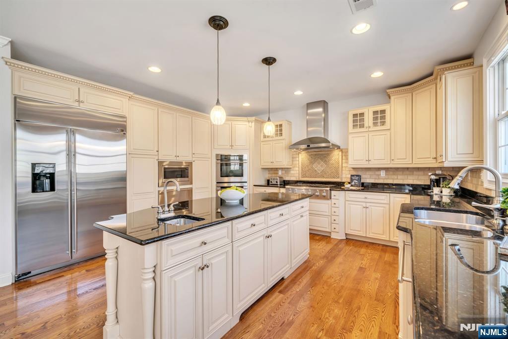 28 Arbor Road North Caldwell, NJ 07006 - Photo 24 of 50 a kitchen with stainless steel appliances kitchen island granite countertop a stove a sink and white cabinets with wooden floor