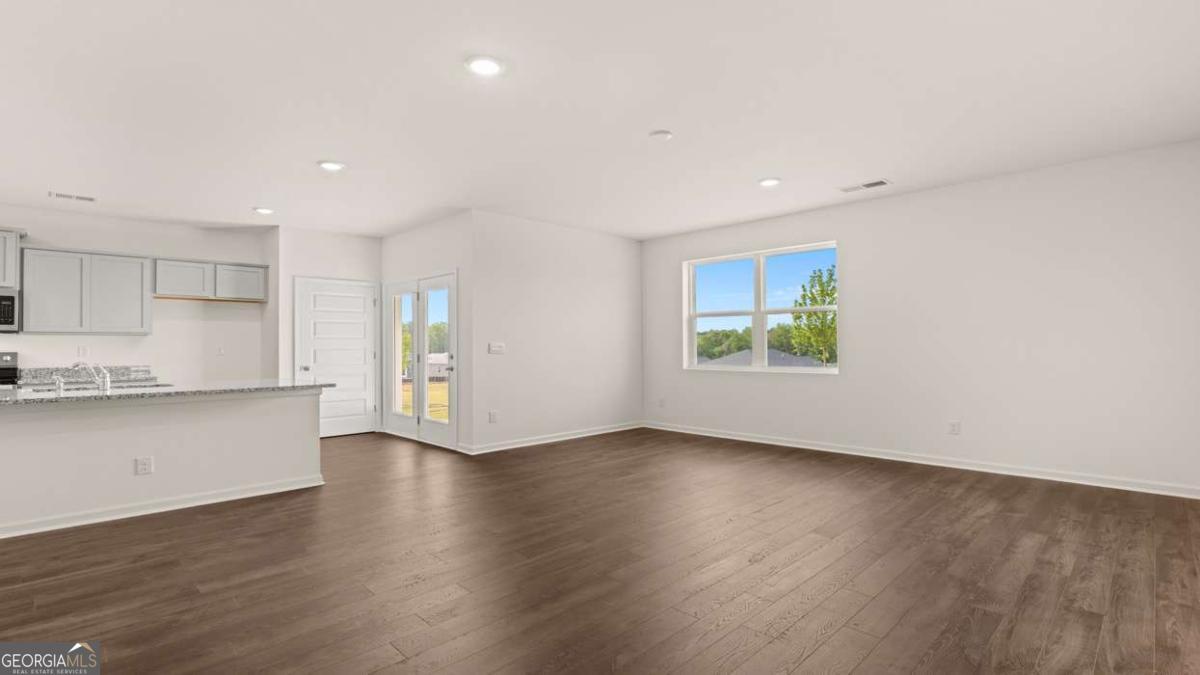 8576 Seabiscuit Road Lithonia, GA 30058 - Photo 7 of 22 a view of an empty room with wooden floor and a window