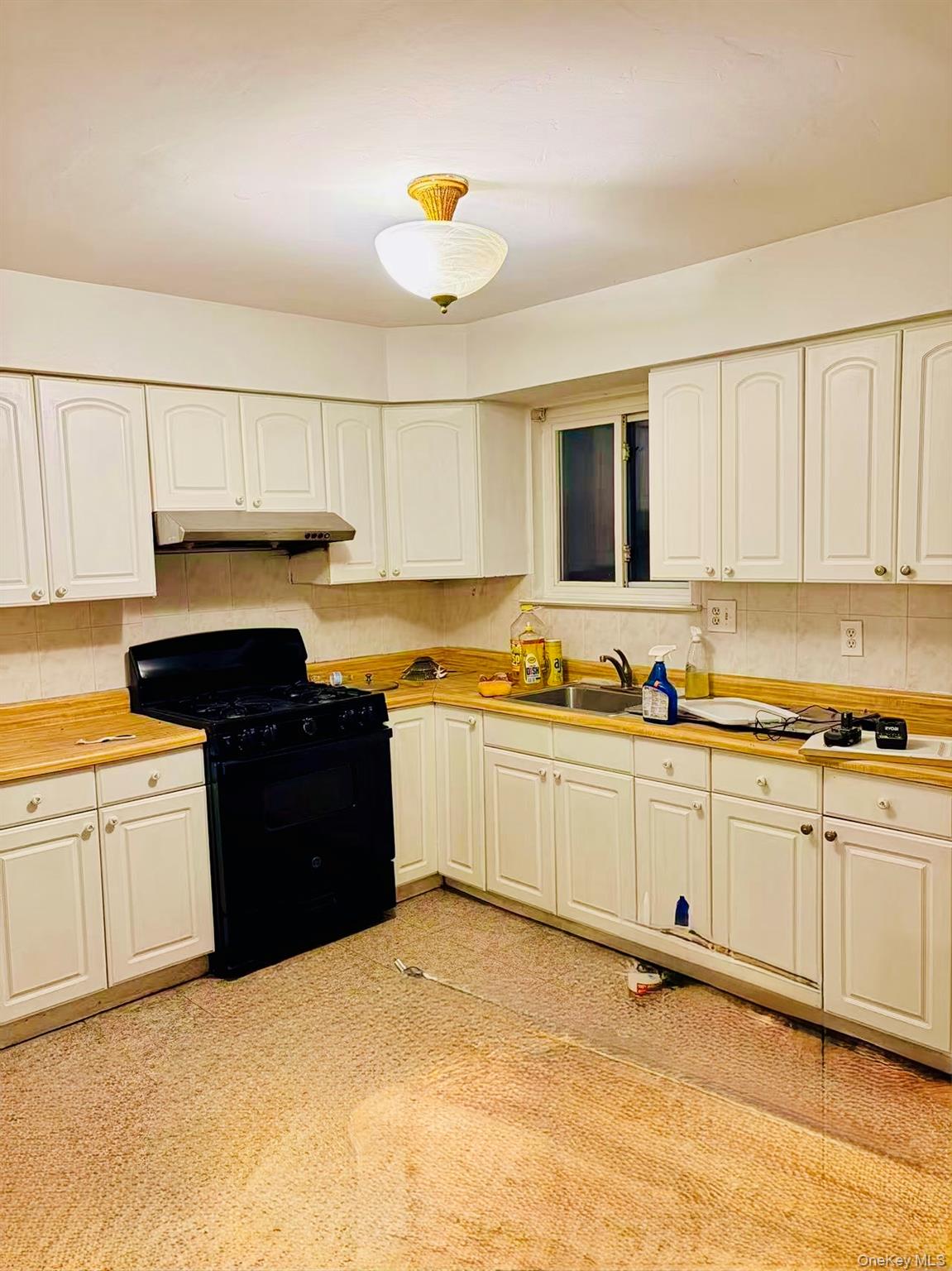 a kitchen with granite countertop a stove top oven sink and cabinets