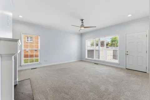 a view of an empty room with a window and a kitchen