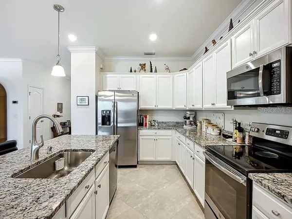 a kitchen with stainless steel appliances granite countertop a sink a stove a refrigerator cabinets and a kitchen island