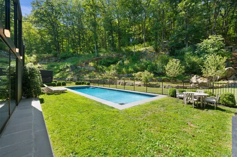 a view of a swimming pool with a patio and a yard
