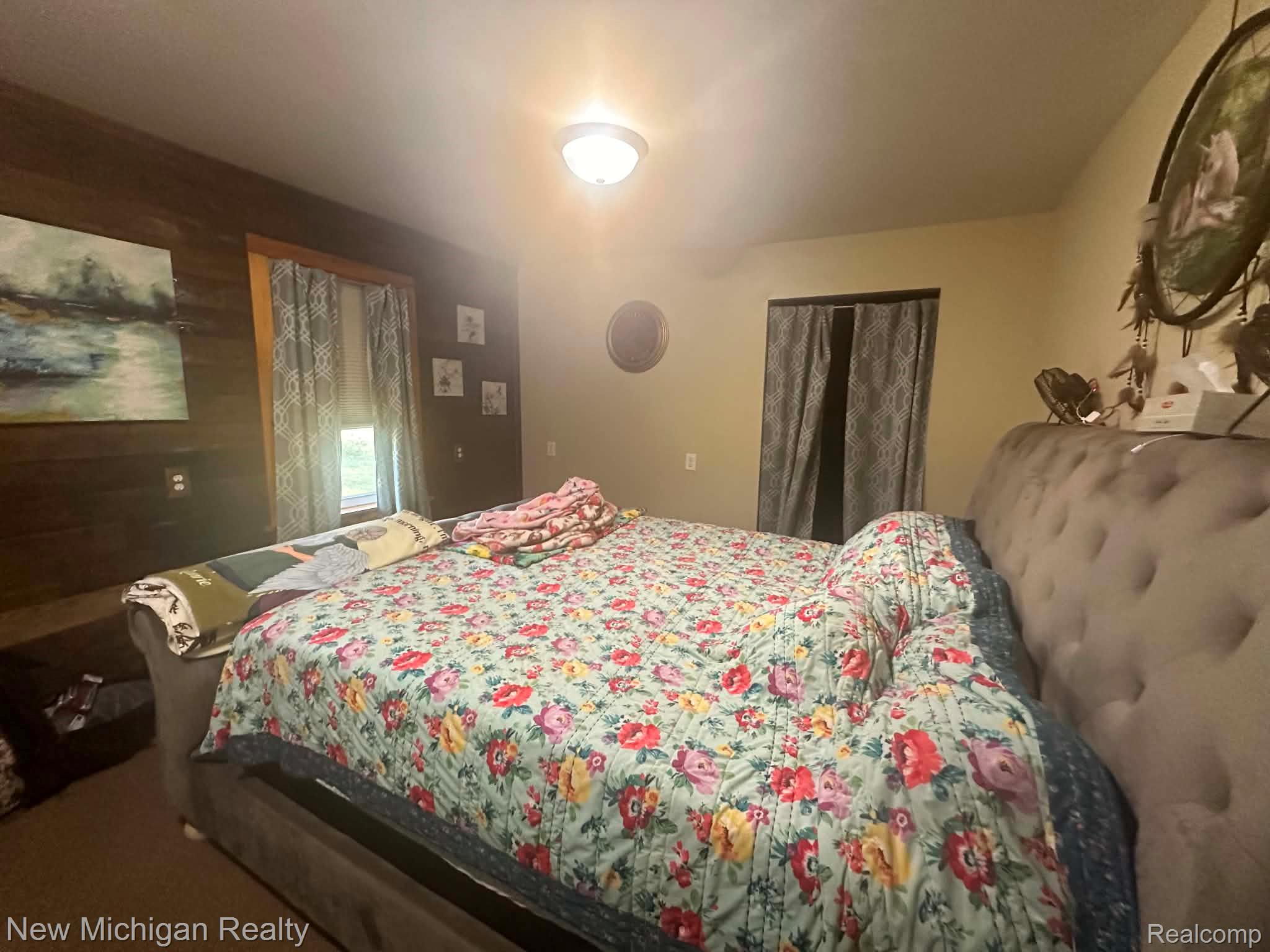 7415 Farrand Road Clio, MI 48420 - Photo 11 of 31 Interior room featuring a wood-panel accent wall, neutral painted walls, and a visible window with patterned drapes