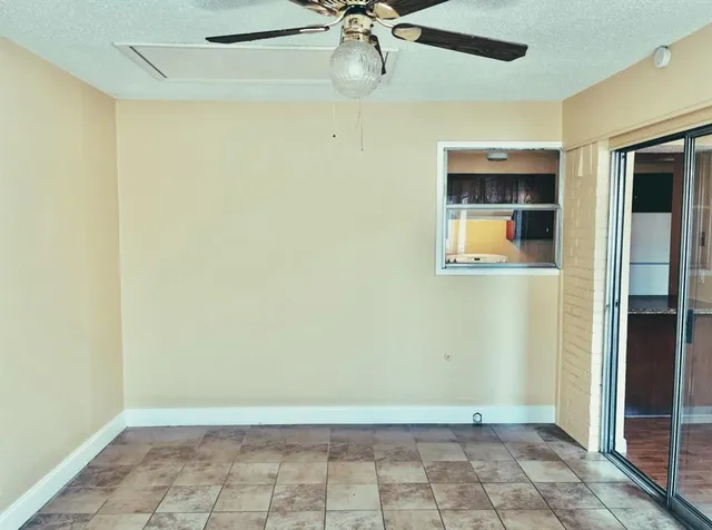 an empty room with a ceiling fan and glass door