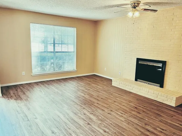 an empty room with wooden floor fan and windows