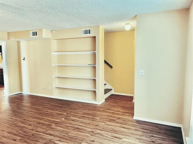 a view of an empty room with wooden floor and a door