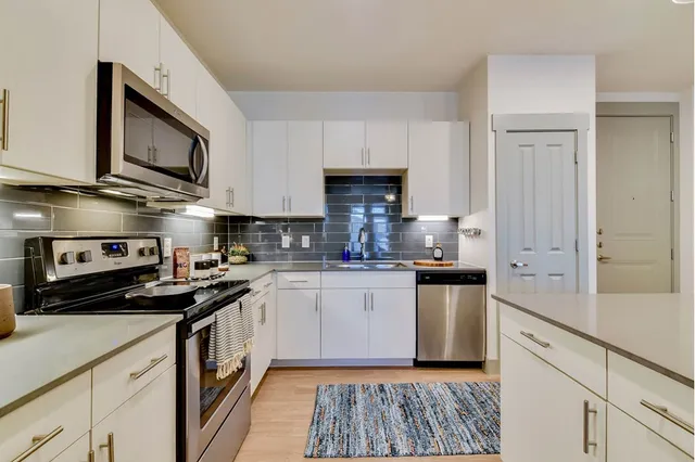 a kitchen with stainless steel appliances granite countertop a stove a sink and a microwave