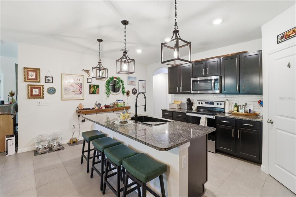 660 Hickory Course Loop Ocala, FL 34472 - Photo 9 of 45 a kitchen with stainless steel appliances granite countertop a stove top oven a sink a dining table and chairs