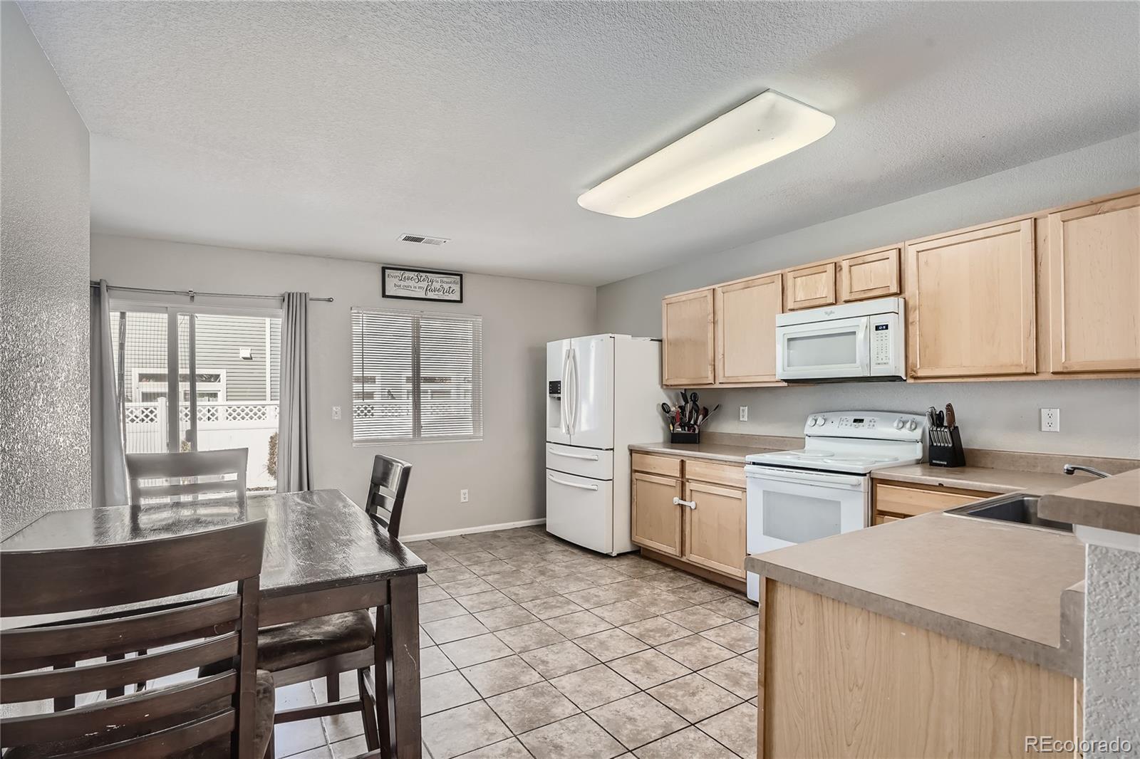 4725 Andes Street Denver, CO 80249 - Photo 7 of 27 a kitchen with a refrigerator a stove cabinets and a dining table