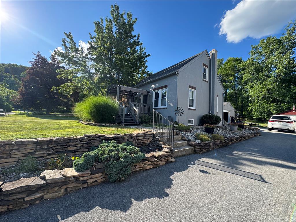 4425 Vera Cruz Road Center Valley, PA 18034 - Photo 2 of 4 A charming gray residence nestled amidst mature trees and a neatly terraced rock wall garden.