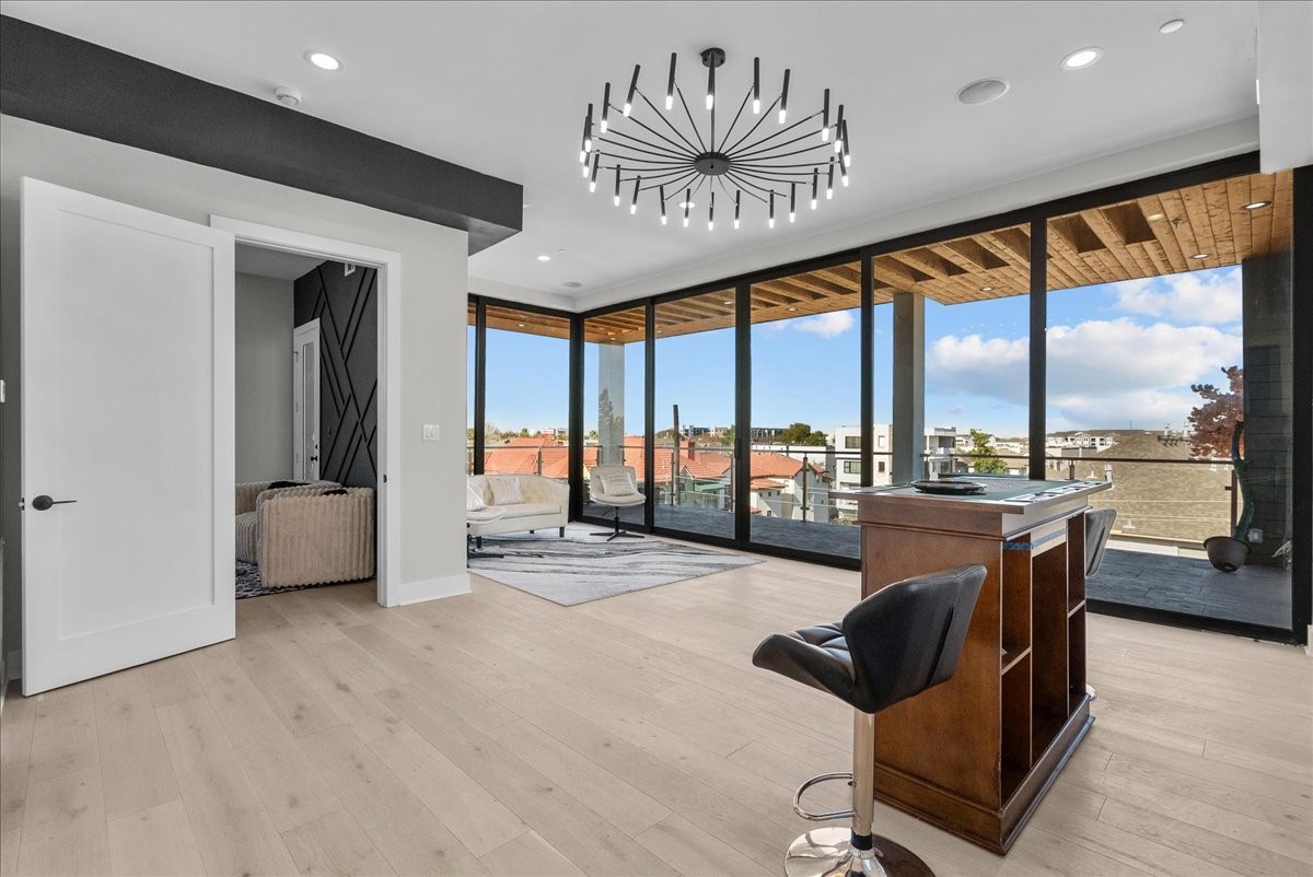 516 Reinerman Street Houston, TX 77007 - Photo 32 of 42 This room features modern design with floor-to-ceiling windows offering expansive city views. It includes a stylish chandelier, light wood flooring, and access to a covered balcony. Perfect for a home office or lounge area.