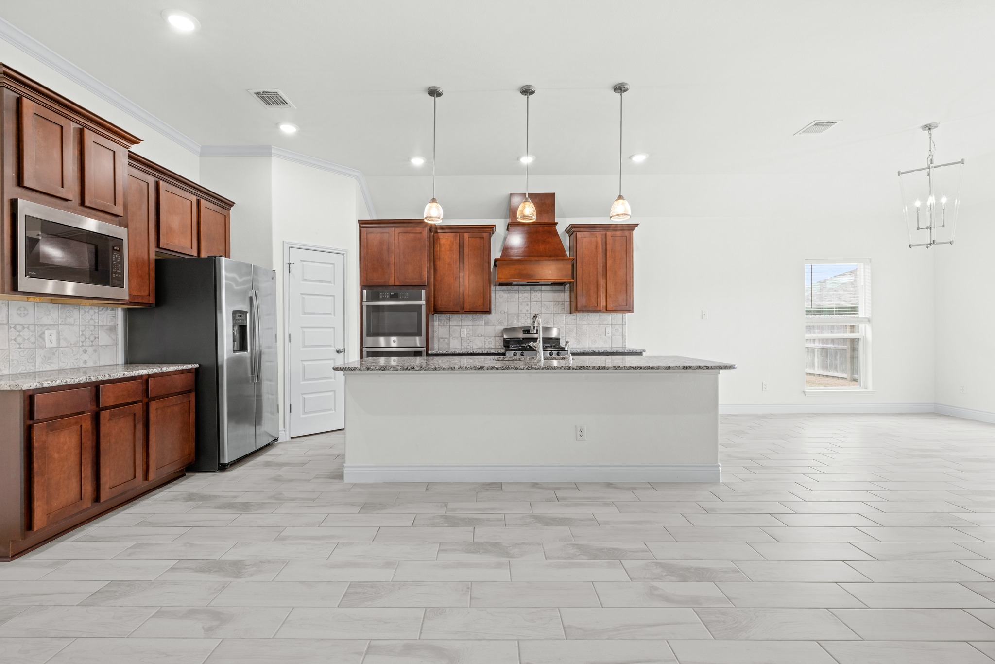 6019 Monza Drive Temple, TX 76502 - Photo 12 of 40 Kitchen featuring light stone countertops, a kitchen island with sink, stainless steel appliances, and pendant lighting