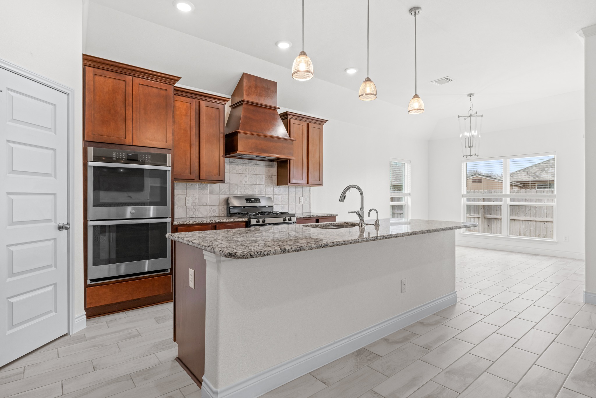 6019 Monza Drive Temple, TX 76502 - Photo 13 of 40 Kitchen with light stone countertops, stainless steel appliances, a kitchen island with sink, tasteful backsplash, and wood finish cabinets