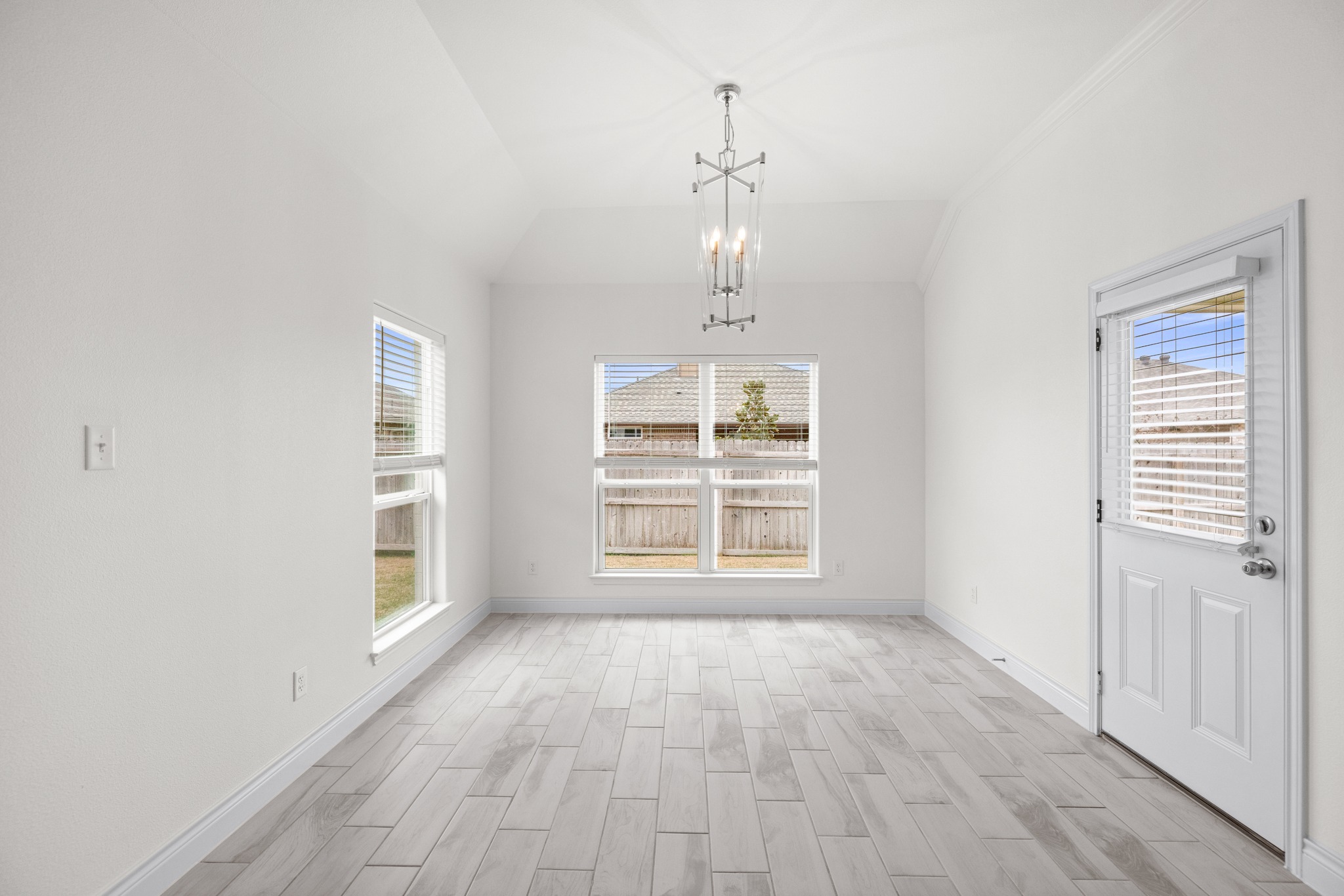 6019 Monza Drive Temple, TX 76502 - Photo 17 of 40 Unfurnished dining area with wood tiled floors, suspended lighting, vaulted ceiling, and healthy amount of natural light
