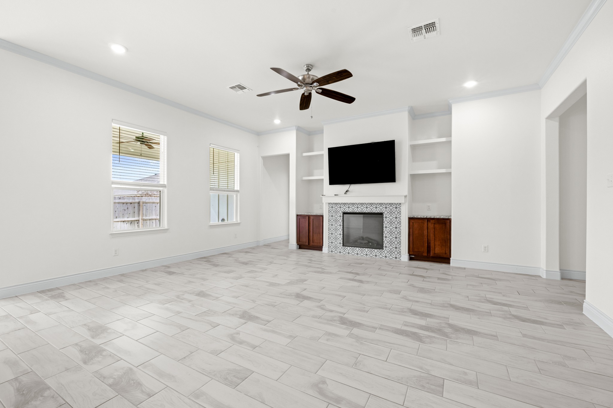 6019 Monza Drive Temple, TX 76502 - Photo 7 of 40 Unfurnished living room featuring built in features, a ceiling fan, crown molding, recessed lighting, and a tiled fireplace