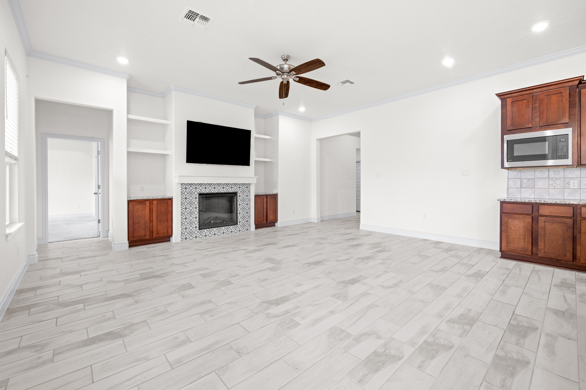 6019 Monza Drive Temple, TX 76502 - Photo 8 of 40 Unfurnished living room featuring built in features, a ceiling fan, ornamental molding, recessed lighting, and a fireplace