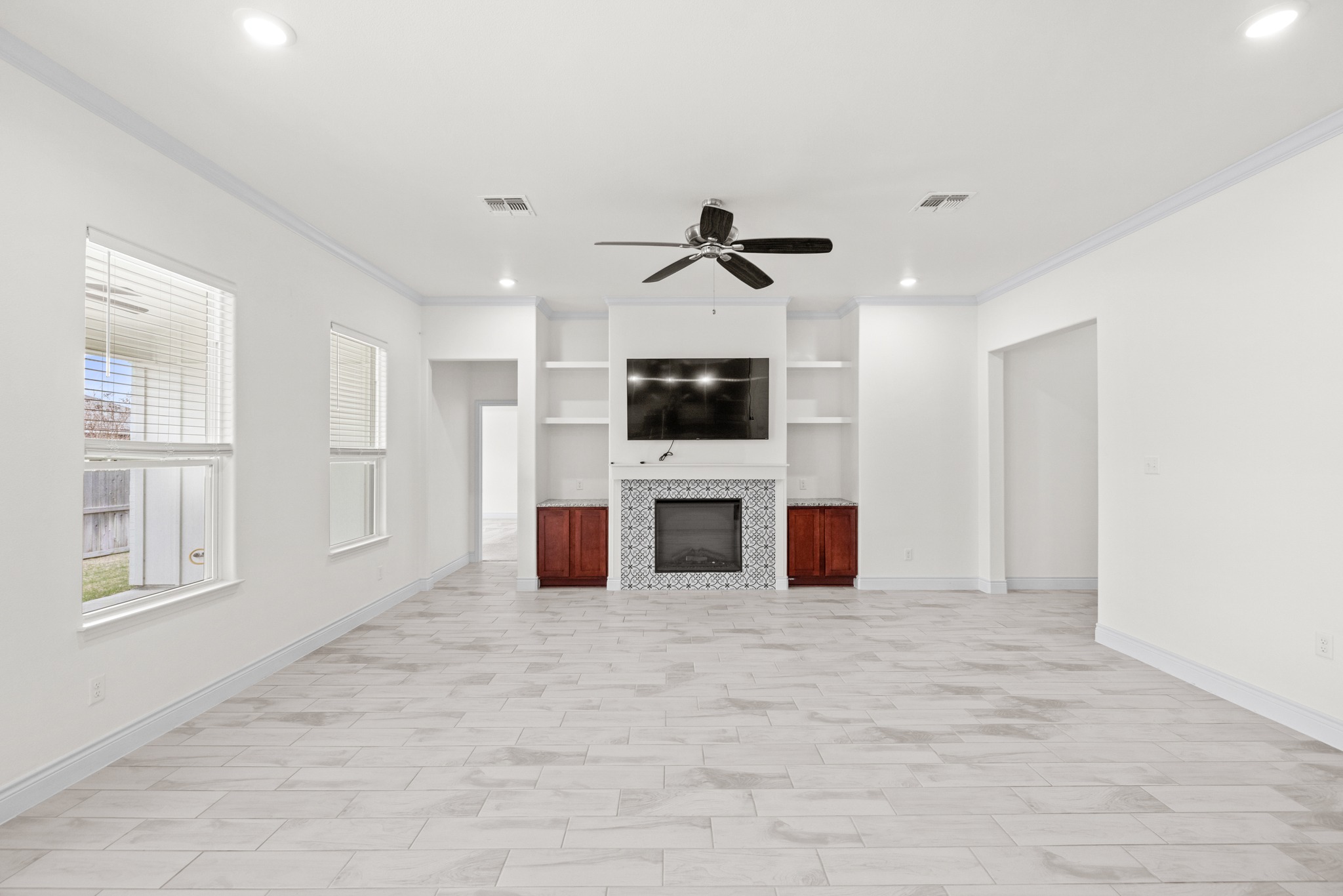 6019 Monza Drive Temple, TX 76502 - Photo 9 of 40 Unfurnished living room featuring a ceiling fan, built in shelves, ornamental molding, recessed lighting, and a tile fireplace