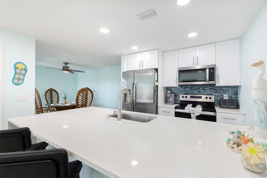 337 Rex Place, Unit G Madeira Beach, FL 33708 - Photo 14 of 40 a kitchen with refrigerator a microwave a stove cabinets and living room view