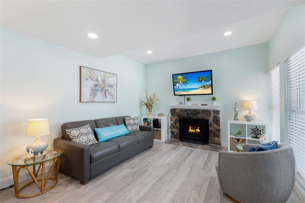 337 Rex Place, Unit G Madeira Beach, FL 33708 - Photo 3 of 40 a living room with furniture a fireplace and a flat screen tv