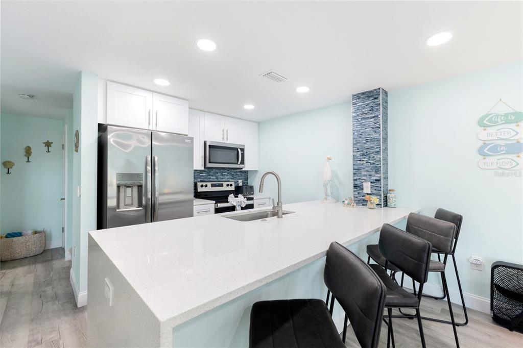 337 Rex Place, Unit G Madeira Beach, FL 33708 - Photo 10 of 40 a kitchen with a dining table chairs and refrigerator