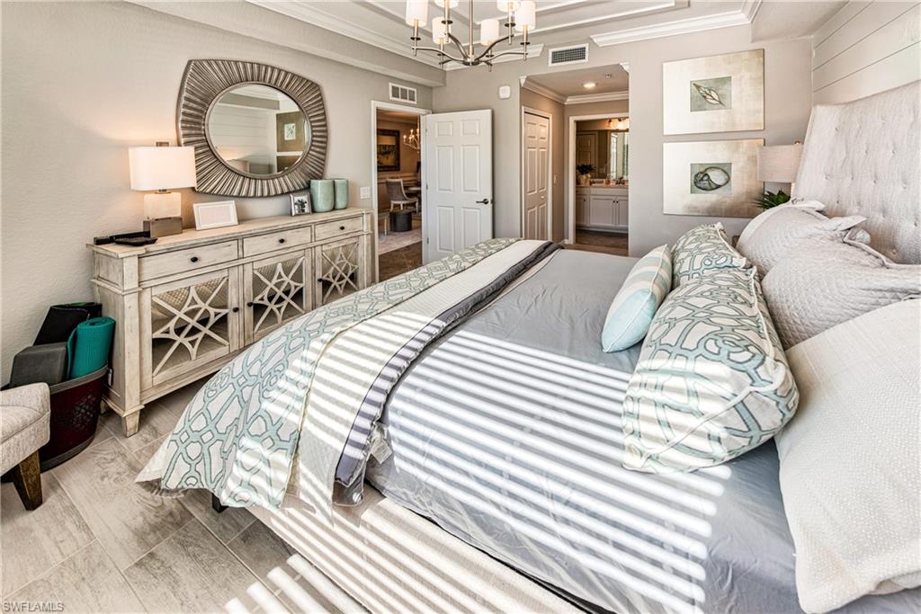 9572 Trevi Court, Unit 5015 Naples, FL 34113 - Photo 11 of 39 a bedroom with bed and a mirror on the dresser
