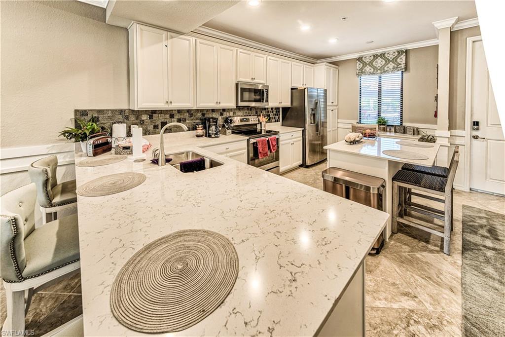 9572 Trevi Court, Unit 5015 Naples, FL 34113 - Photo 7 of 39 a kitchen with stainless steel appliances sink microwave and stove