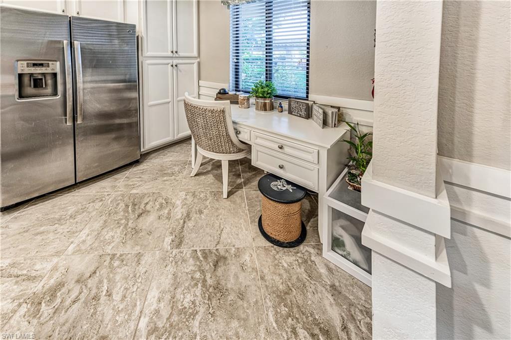 9572 Trevi Court, Unit 5015 Naples, FL 34113 - Photo 9 of 39 a bathroom with a granite countertop sink and a refrigerator