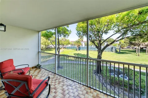 a balcony with chairs in front of a yard