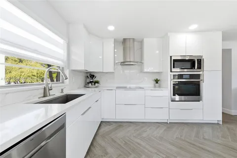 a kitchen with granite countertop a sink stainless steel appliances and white cabinets