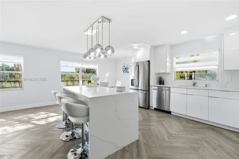 a kitchen with stainless steel appliances a dining table chairs a refrigerator and cabinets