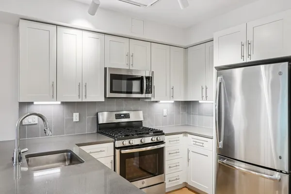 a kitchen with stainless steel appliances white cabinets and a refrigerator
