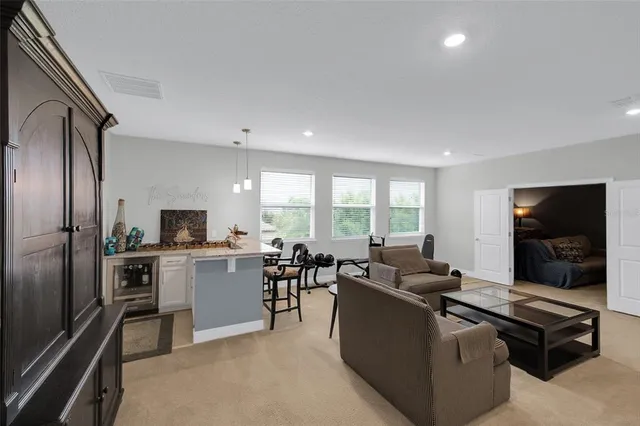 a living room with stainless steel appliances kitchen island granite countertop a sink and a refrigerator