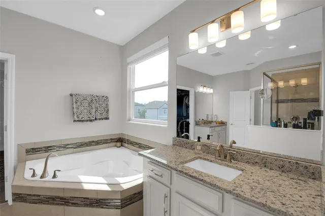 a bathroom with a granite countertop tub sink and mirror