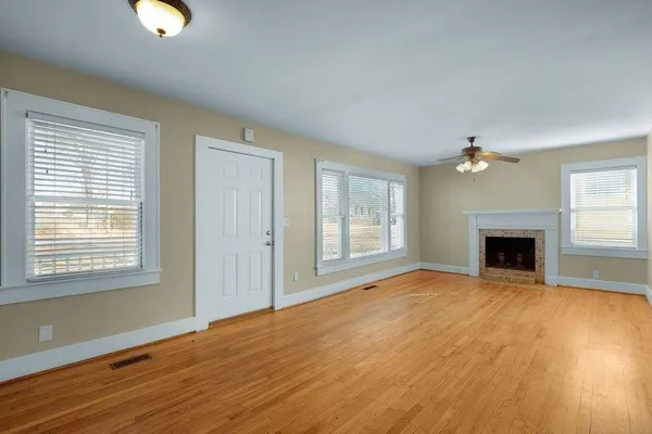 a view of an empty room with window and wooden floor