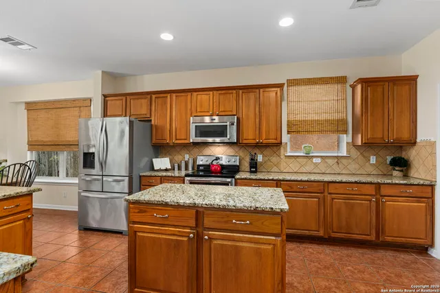 a kitchen with kitchen island granite countertop a stove top oven a sink dishwasher a refrigerator and cabinets with wooden floor