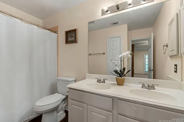 a bathroom with a granite countertop sink toilet and a mirror