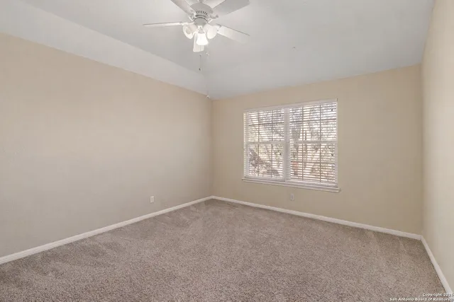 an empty room with a window and a fan