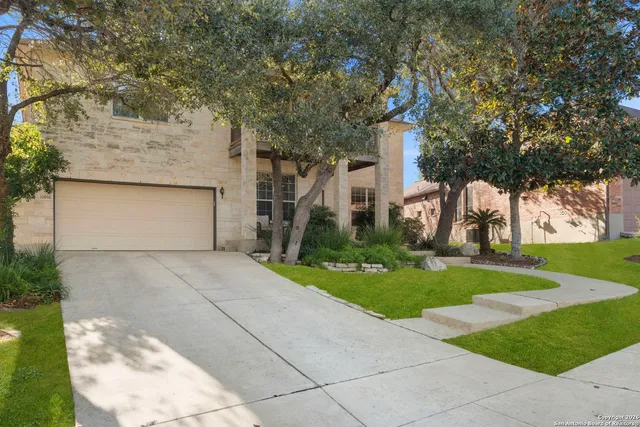 front view of house with a yard and trees all around