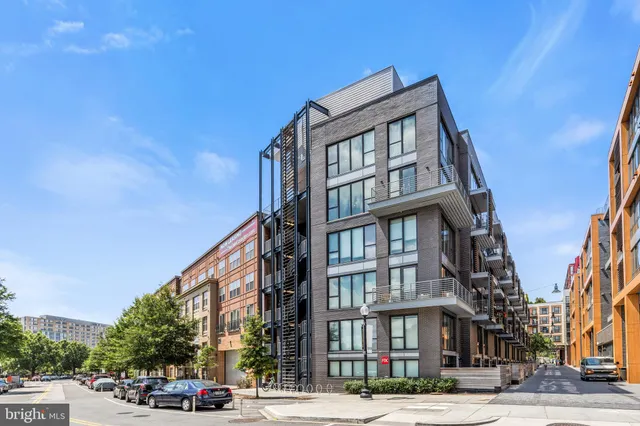 a front view of a building with lot of cars and trees