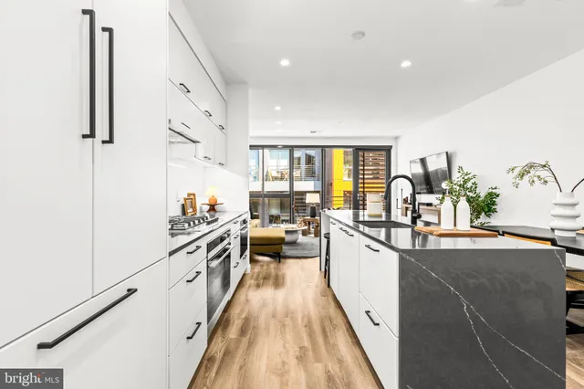 a large kitchen with stainless steel appliances a lot of counter space and a wooden floor