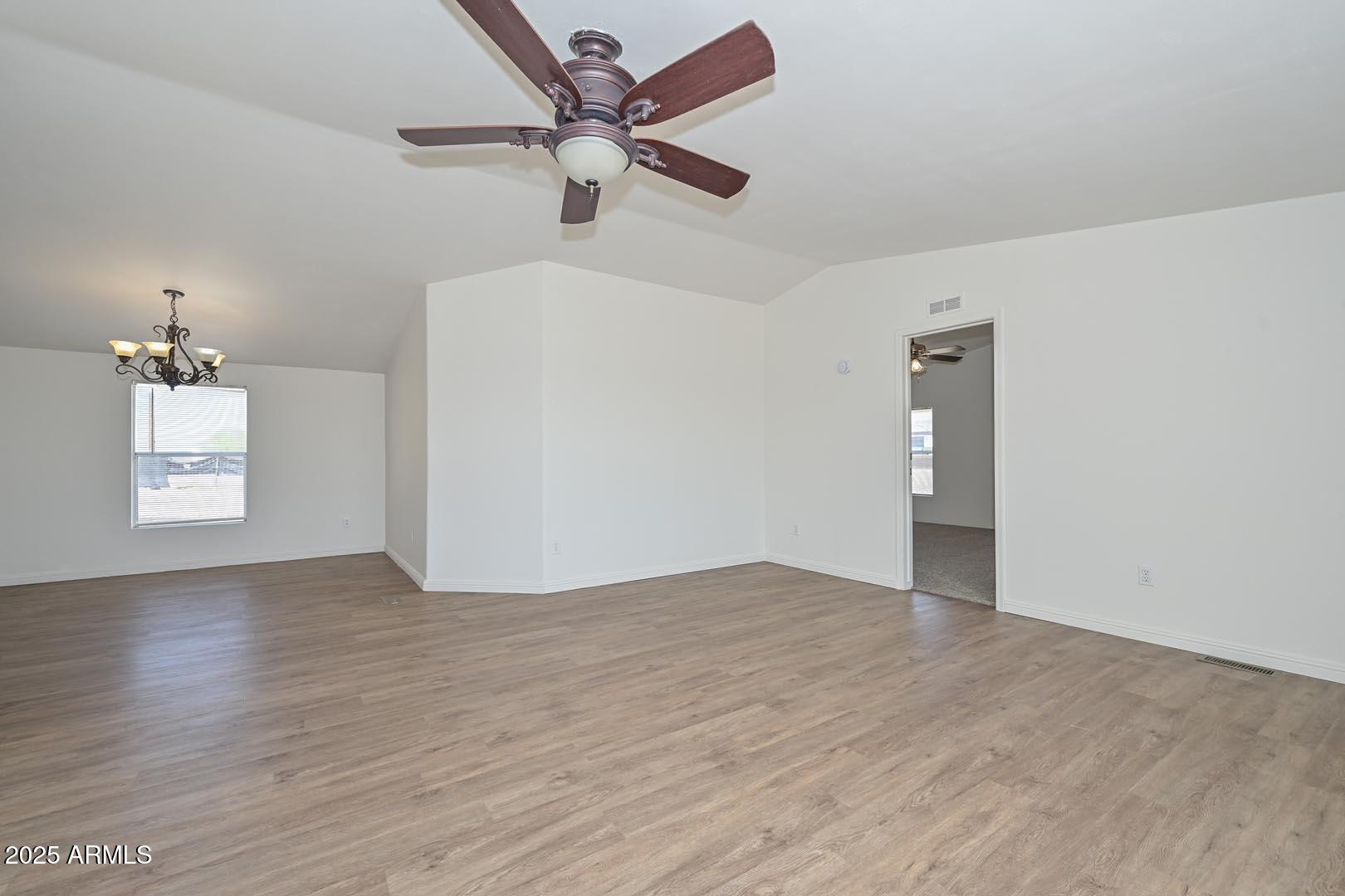 36608 West Lower Buckeye Road Tonopah, AZ 85354 - Photo 10 of 39 an empty room with wooden floor chandelier fan and windows